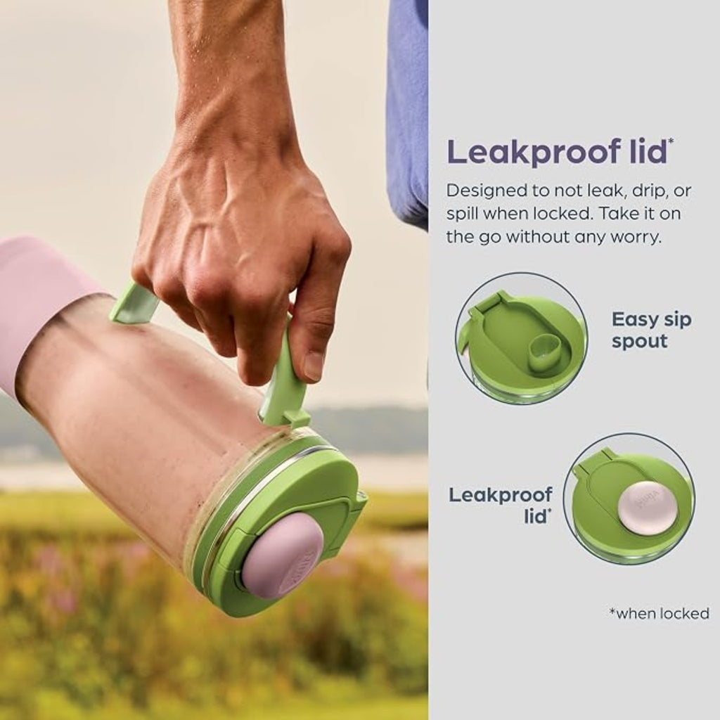 Hand holding a green and pink container with leakproof lid feature, set against a natural background.