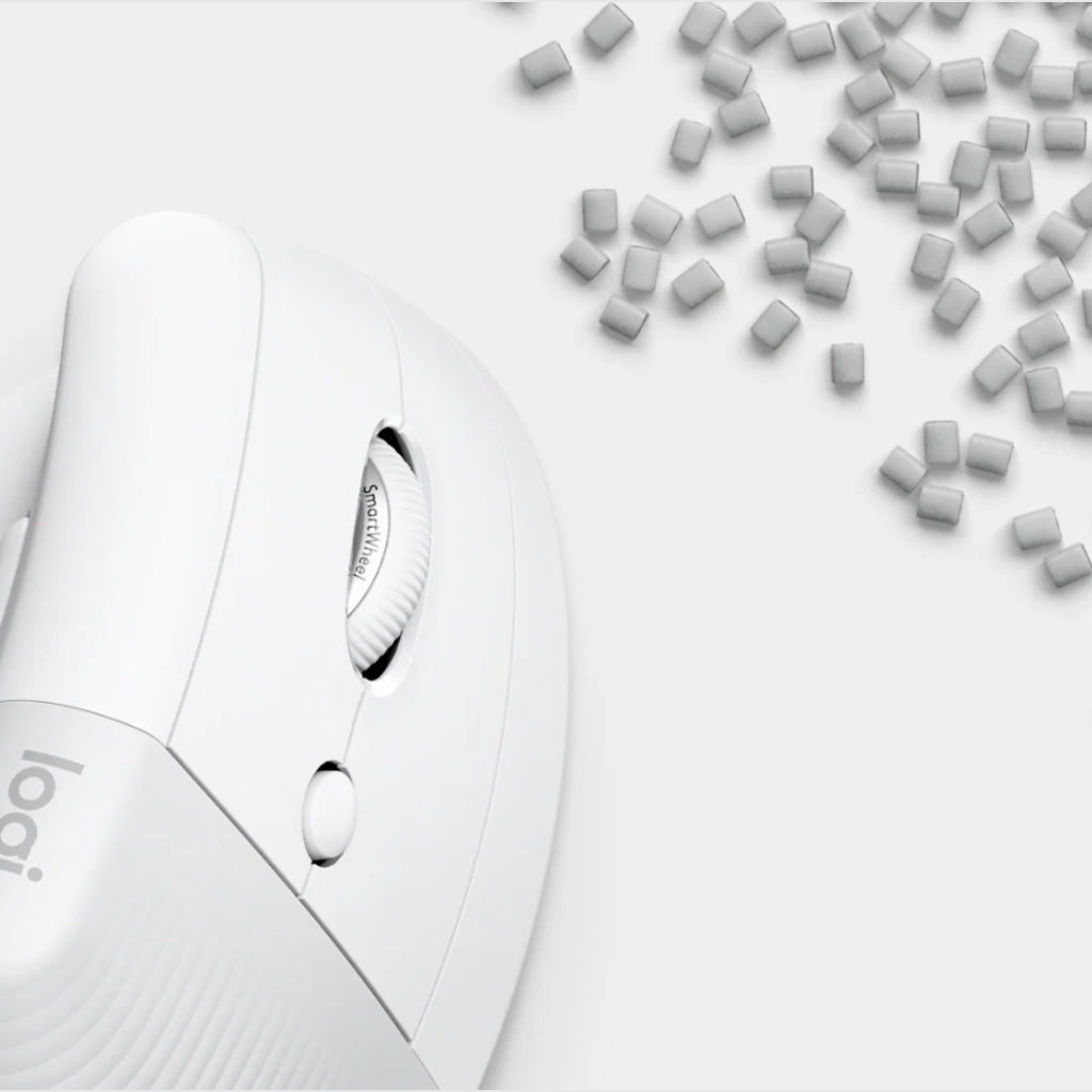 A close-up of a white Logitech computer mouse on a light gray background, with small gray rectangular pieces scattered in the upper right corner.